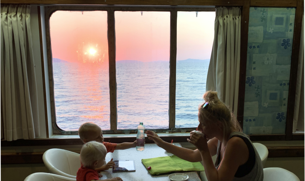 3 poeple travelling with a ferry seeing a sunset in the window